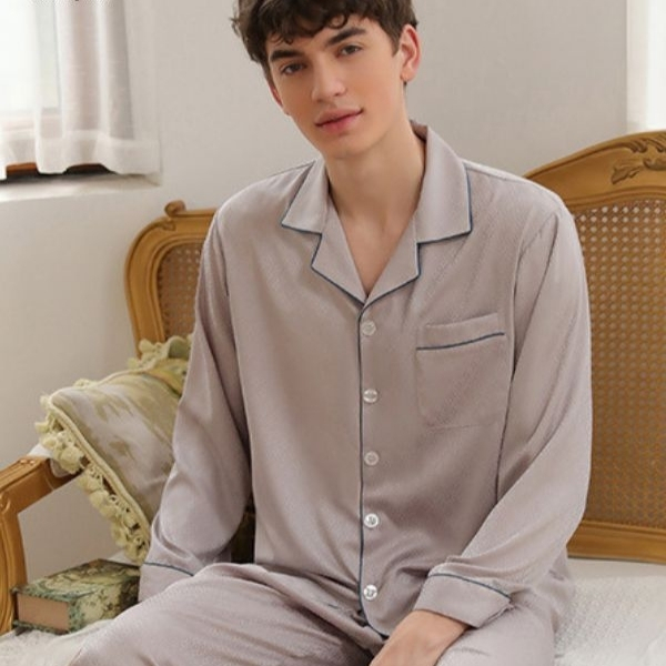 Bộ pijama nam dài tay màu be chất liệu lụa mềm mại ngồi trên ghế trong phòng ngủ