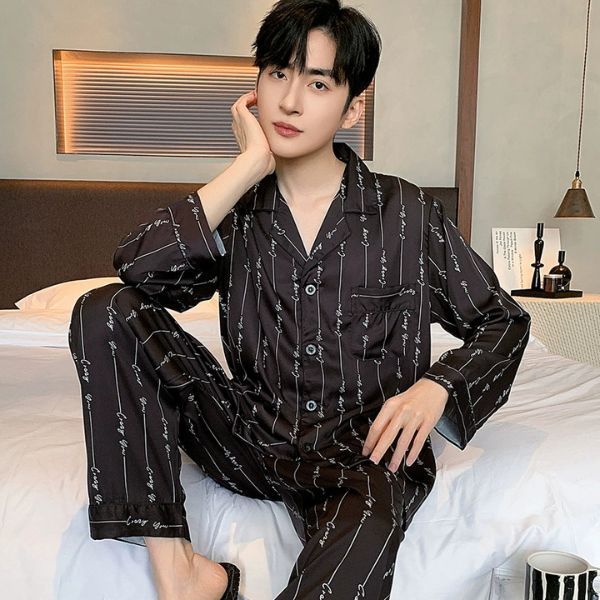 Bộ pijama lụa nam màu đen họa tiết chữ, dáng dài tay quần dài ngồi trên giường ngủ