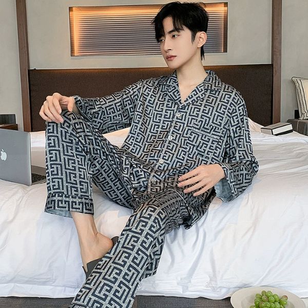 Nam giới mặc bộ pijama dài tay họa tiết hình học màu xám đen ngồi trên giường trong phòng ngủ hiện đại