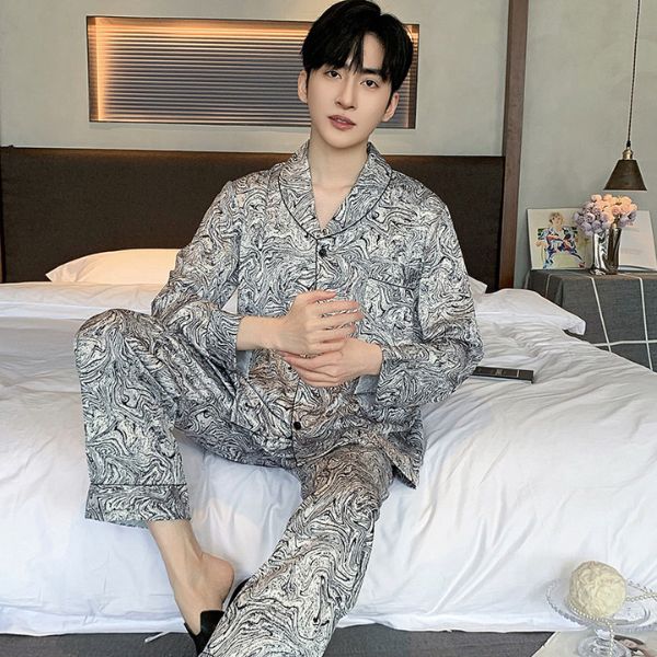 Nam giới mặc bộ pijama dài tay họa tiết marble màu xám ngồi trên giường trong phòng ngủ hiện đại