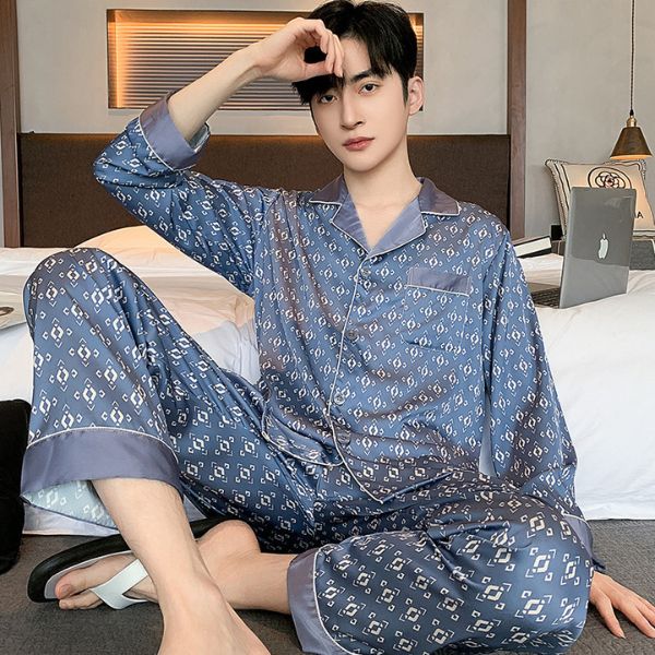 Nam giới mặc bộ pijama lụa dài tay màu xanh họa tiết nhỏ ngồi trên giường trong phòng ngủ
