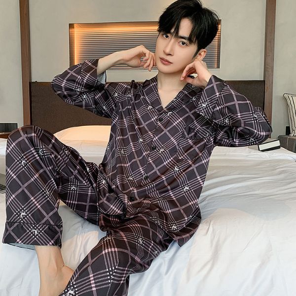 Nam giới mặc bộ pijama dài tay kẻ caro màu tối ngồi trên giường trong phòng ngủ hiện đại