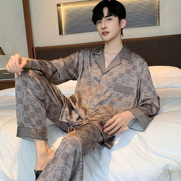 Nam giới mặc bộ pijama lụa dài tay màu nâu họa tiết hình học ngồi trên giường ngủ