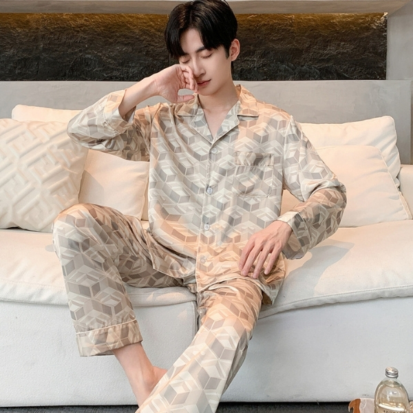 Nam giới mặc bộ pijama lụa họa tiết hình khối màu be ngồi thư giãn trên ghế sofa trắng