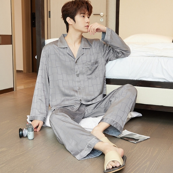 Nam giới mặc bộ pijama lụa màu xám dài tay quần dài ngồi trên sàn cạnh giường ngủ
