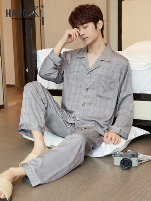 Nam giới mặc bộ pijama lụa màu xám dài tay quần dài ngồi thư giãn cạnh giường ngủ