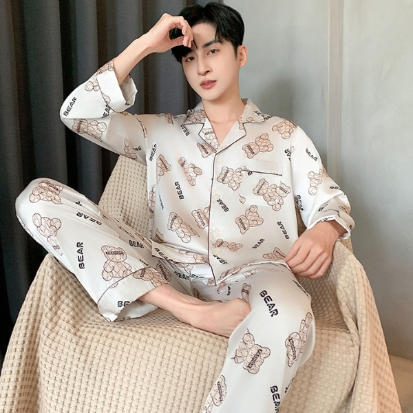 Nam giới mặc bộ pijama lụa dài tay họa tiết gấu teddy màu trắng ngồi trên ghế vải mềm