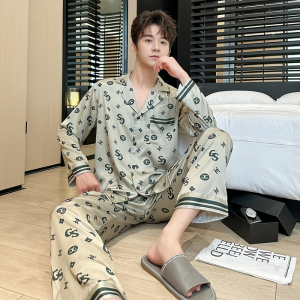 Bộ pijama lụa nam màu be họa tiết chữ GS, dáng dài tay quần dài, người mẫu ngồi trong phòng ngủ hiện đại