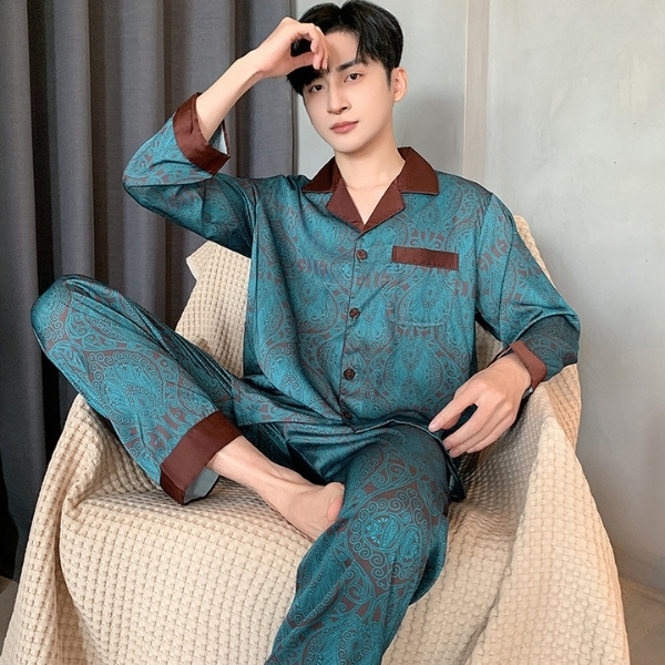 Bộ pijama lụa nam màu xanh họa tiết paisley viền nâu dài tay quần dài ngồi trên ghế vải màu be