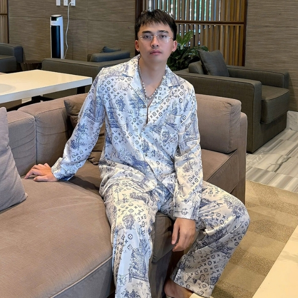 Nam giới mặc bộ pijama lụa họa tiết Louis Vuitton màu trắng xanh ngồi trên ghế sofa trong phòng khách