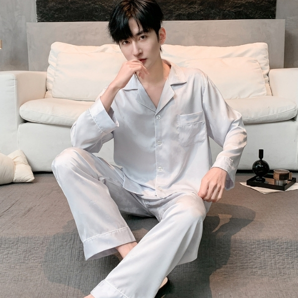 Bộ pijama lụa dài tay màu trắng cho nam ngồi trên giường trong phòng ngủ hiện đại