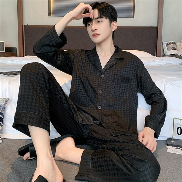 Nam giới mặc bộ pijama lụa màu đen dài tay quần dài ngồi trên giường trong phòng ngủ
