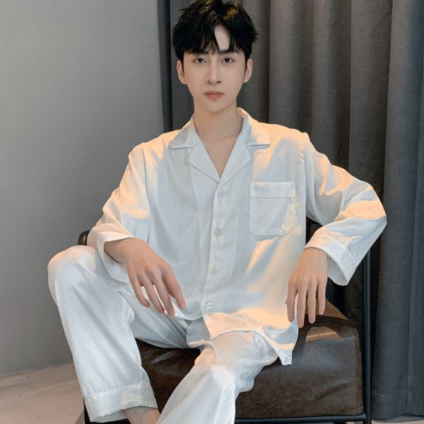 Bộ pijama lụa nam màu trắng dài tay quần dài dáng rộng ngồi trên ghế trong phòng ngủ