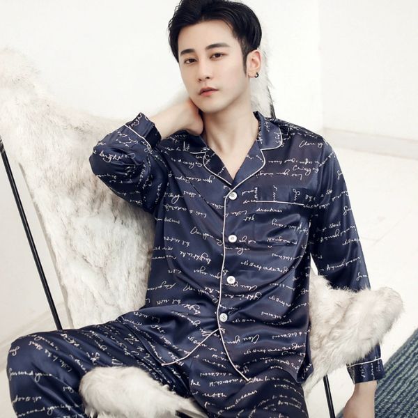 Nam giới mặc bộ pijama lụa màu xanh navy họa tiết chữ ngồi trên ghế lông trắng