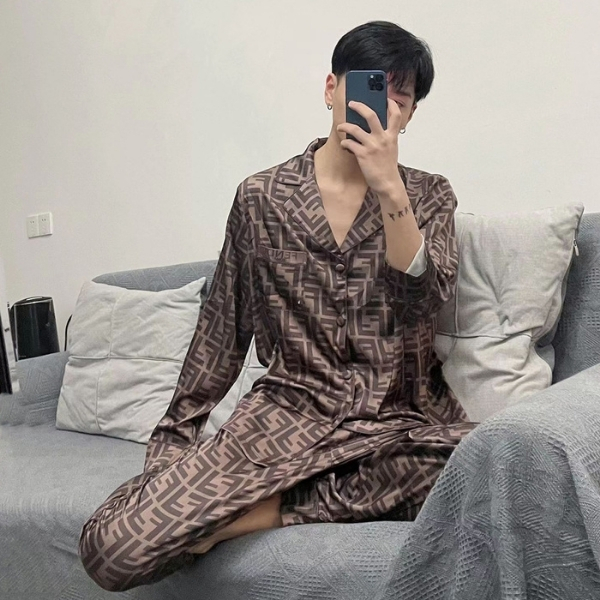 Nam giới mặc bộ pijama lụa họa tiết nâu ngồi trên sofa xám cầm điện thoại chụp ảnh
