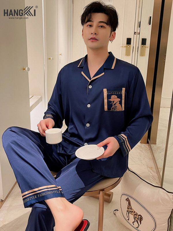 Nam giới mặc bộ pijama lụa xanh navy tay dài quần dài, cầm tách trà trong phòng ngủ hiện đại
