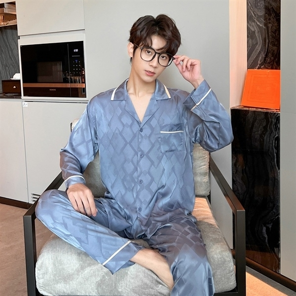 Nam giới mặc bộ pijama lụa màu xanh xám dài tay ngồi trên ghế trong phòng ngủ hiện đại