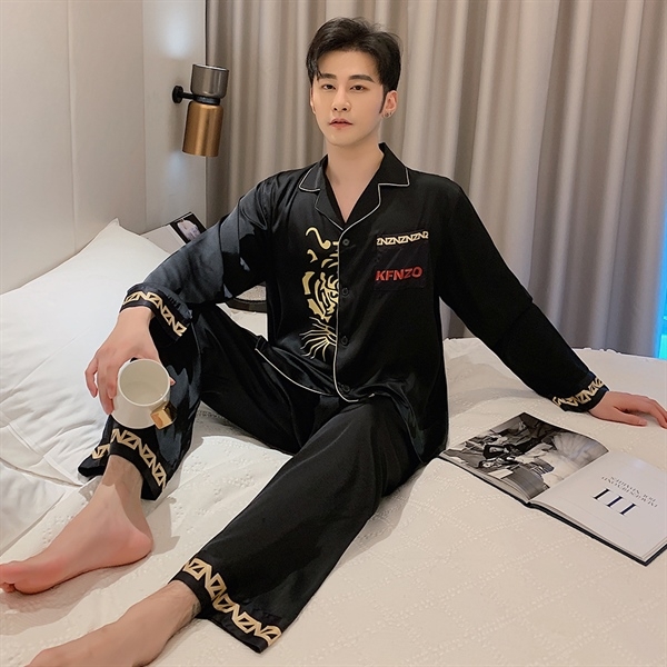 Nam giới mặc bộ pijama lụa đen tay dài họa tiết hổ ngồi trên giường cầm cốc trắng