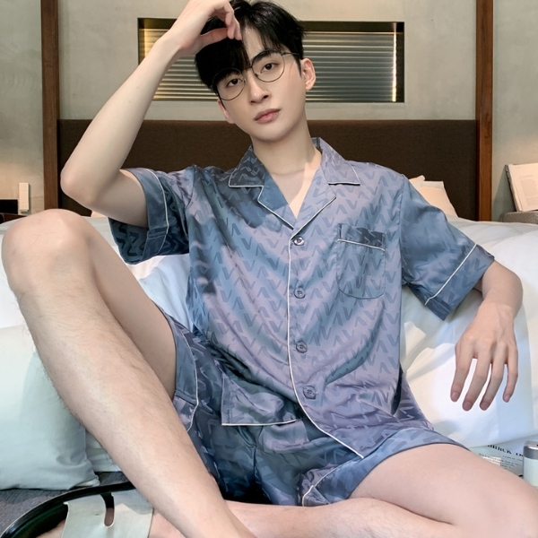 Bộ pijama lụa nam tay ngắn màu xanh họa tiết chữ V ngồi trên giường trong phòng ngủ