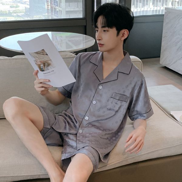 Nam giới mặc bộ pijama lụa ngắn tay màu xám ngồi trên sofa đọc tạp chí
