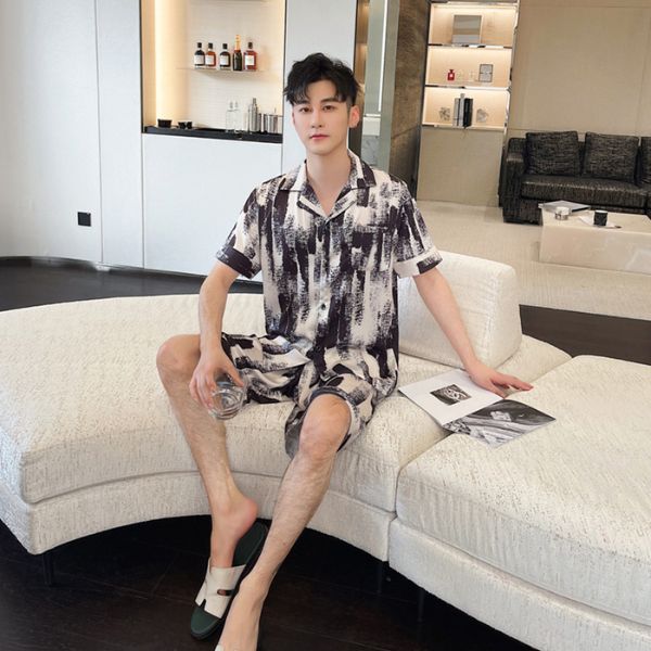 Nam giới mặc bộ đồ ngủ lụa họa tiết đen trắng ngồi trên sofa trong phòng khách hiện đại