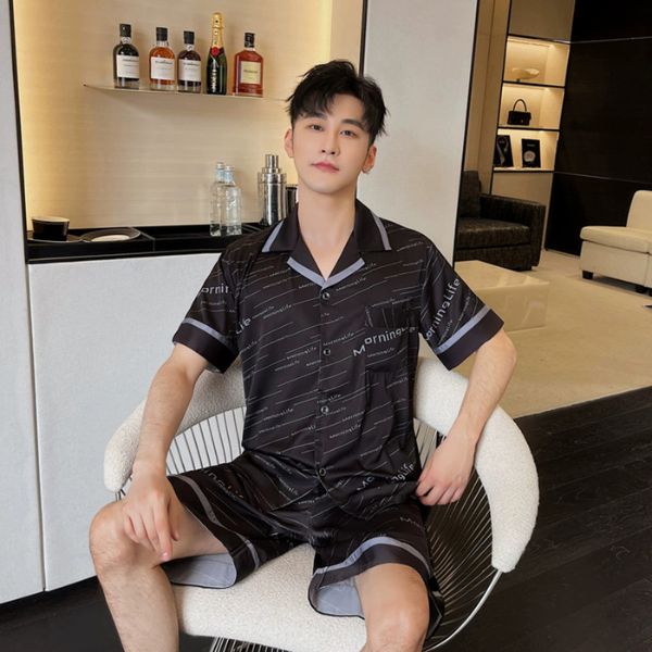 Bộ đồ ngủ nam lụa màu đen tay ngắn quần đùi họa tiết chữ người mẫu ngồi trên ghế trong phòng khách