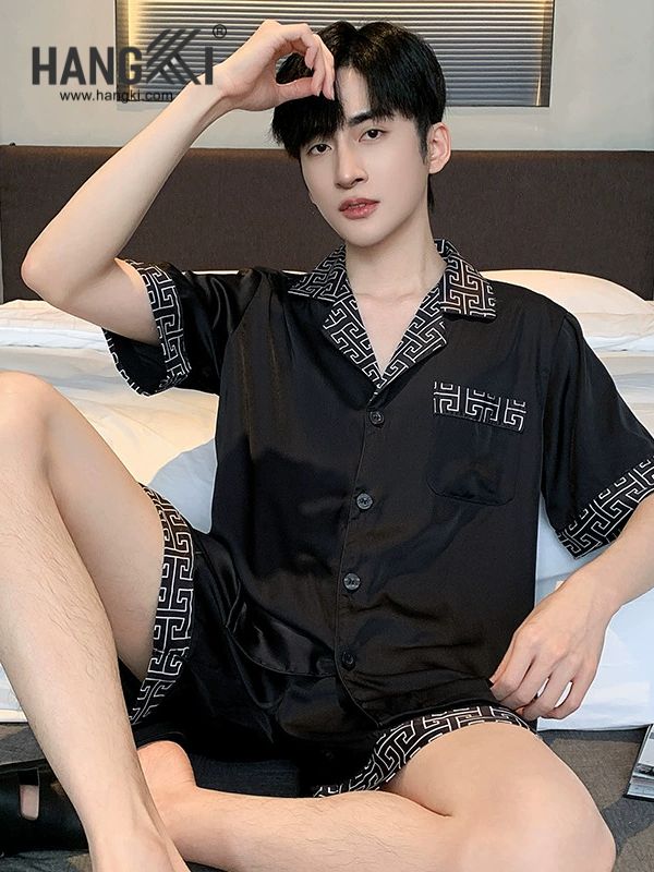 Nam giới mặc bộ đồ ngủ lụa đen tay ngắn họa tiết viền trắng ngồi trên giường
