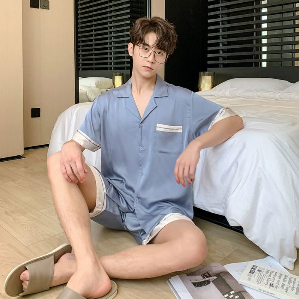 Nam giới mặc bộ pijama lụa xanh tay ngắn quần short ngồi trên sàn cạnh giường ngủ