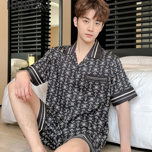 Bộ đồ ngủ nam lụa màu đen họa tiết chữ trắng ngồi trên sàn cạnh giường ngủ