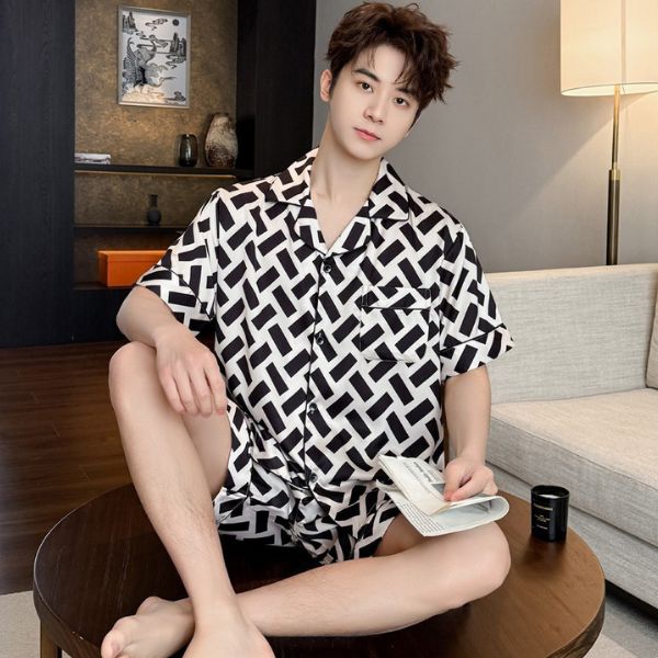 Nam giới mặc bộ pijama lụa họa tiết đen trắng ngồi trên bàn gỗ trong phòng khách hiện đại