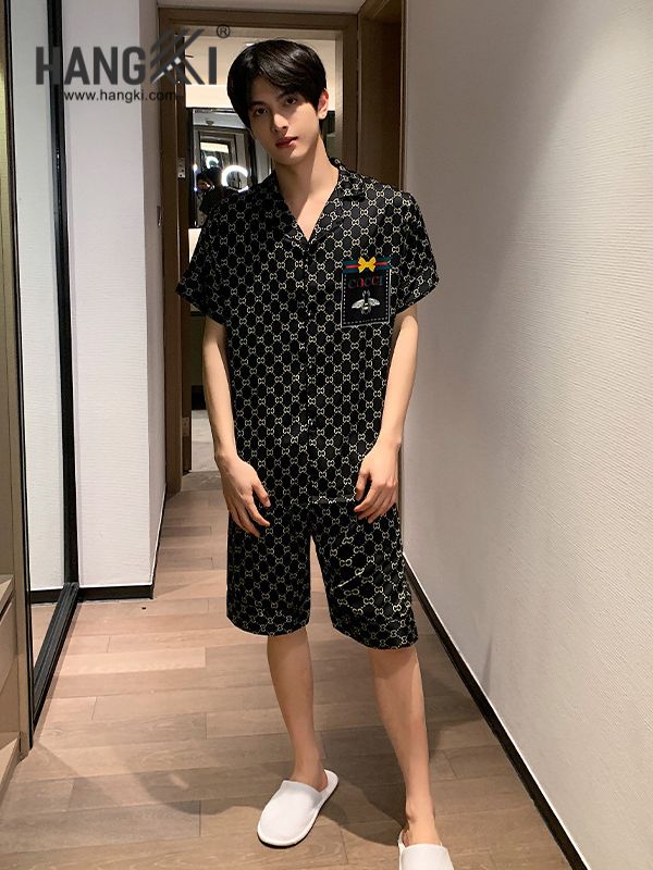 Nam giới mặc bộ đồ ngủ lụa ngắn tay màu đen họa tiết logo Gucci đứng trong hành lang