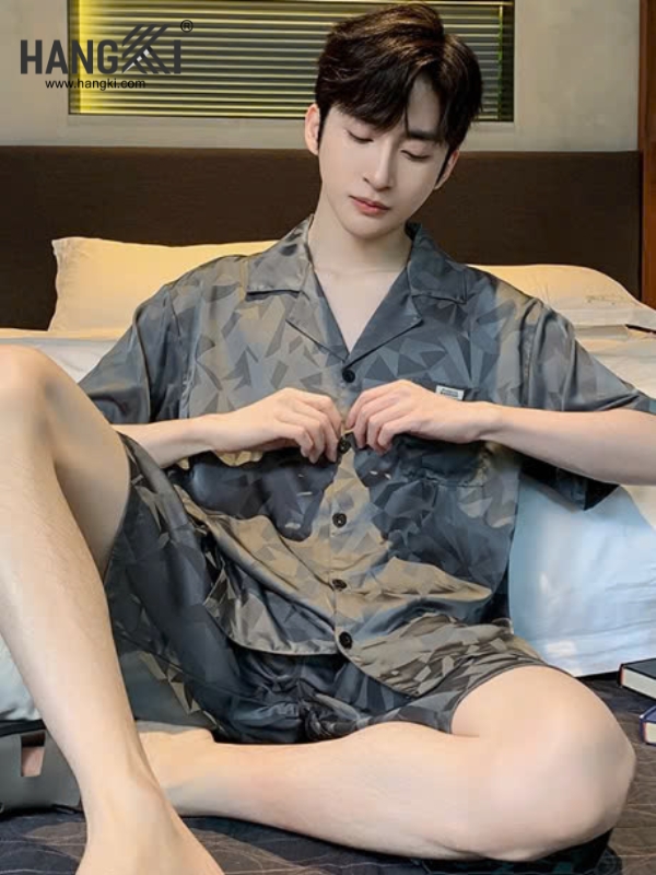 Nam giới mặc bộ đồ ngủ lụa ngắn tay họa tiết hình học màu xám ngồi trên giường