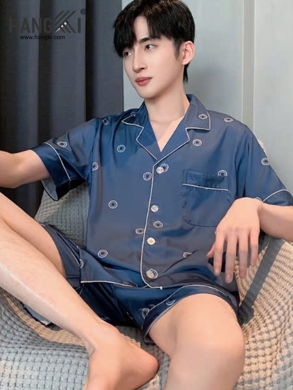 Nam giới mặc bộ pijama lụa xanh navy tay ngắn quần đùi họa tiết chấm tròn ngồi trên ghế sofa
