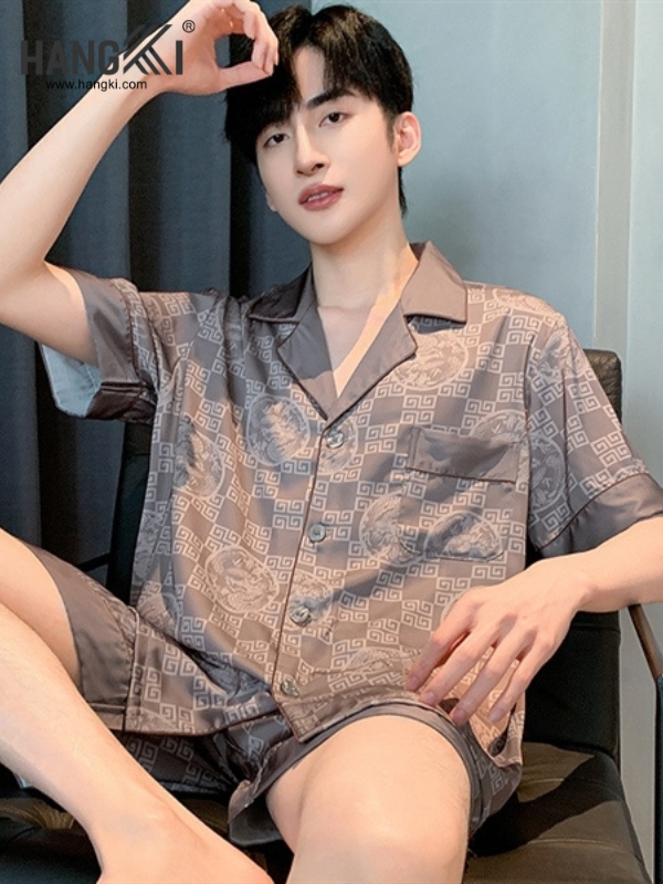 Bộ đồ ngủ nam lụa màu nâu họa tiết hình học ngồi trên ghế trong phòng ngủ