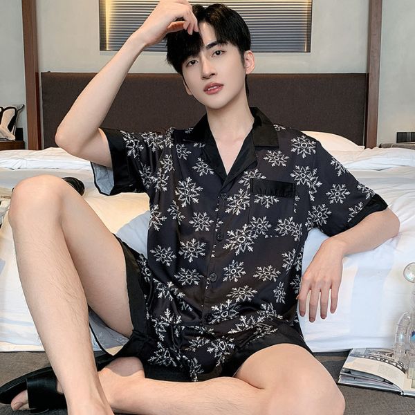 Bộ đồ ngủ nam lụa màu đen họa tiết hoa tuyết trắng ngồi trên giường trong phòng ngủ