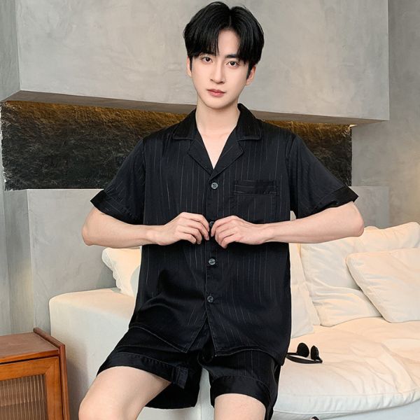 Bộ đồ ngủ nam lụa màu đen tay ngắn quần short, dáng rộng, người mẫu ngồi trên ghế sofa